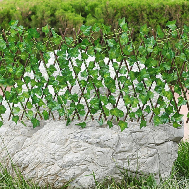 A wall fence made of artificial green leaves, varying in size from 50 to 200 cm
